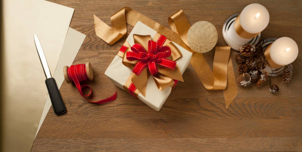 Boîte de cadeau de Noel attachée avec l'arc rouge et d'or au-dessus d'une table en bois - Photo