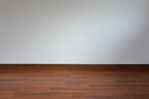 Wide angle interior shot of an empty room with a timber window, wood floors and curtains. View to outside is of a wooden fence.