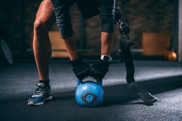 istock Adaptive athlete with a prosthetic leg doing a sport exercise with a kettlebell in a gym 1186921640