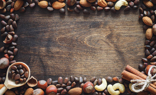istock Different nuts on a wooden table. Cedar, cashew, hazelnut, walnuts and a spoon on the table. Many nuts are inshell and chistchenyh on a wooden background. 1186921849