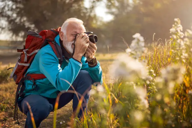 Photo of Traveler hiker man with backpack hiking near lake taking photos