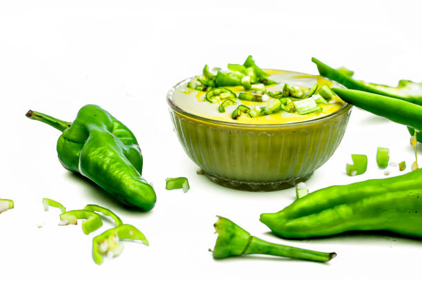 Raw cut green chili isolated on the white surface along with its tangy spicy green chili sauce in a glass bowl. Horizontal shot. Raw cut green chili isolated on the white surface along with its tangy spicy green chili sauce in a glass bowl. Horizontal shot. tangy stock pictures, royalty-free photos & images