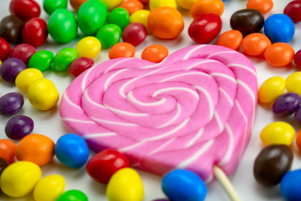 colourful candies and pink lollipop  on a white background close up selective focus, unhealthy eating and kids party food concept