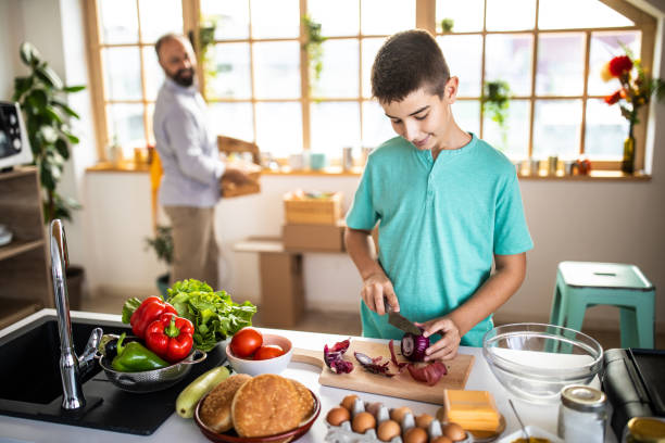 istock Teenage boy cutting Spanish onion in kitchen 1186928213