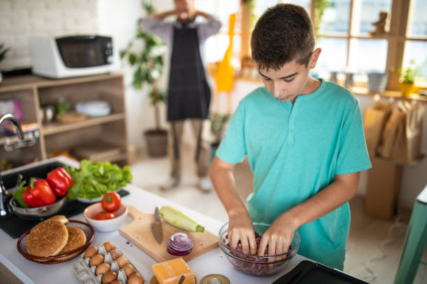 istock Teenage boy mixing ground beef at kitchen 1186928345