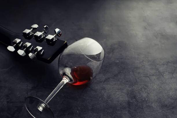 istock Guitar and high glass with red wine on a stone background. 1186931859