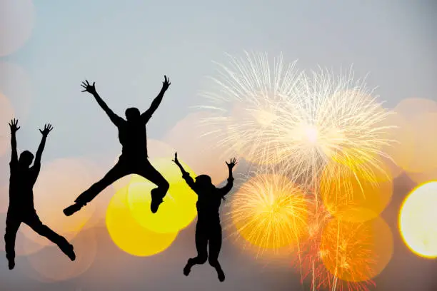 Photo of Silhouette happy business teamwork jumping and cheering crowd fireworks congratulation graduation in Happy New year 2020. Freedom lifestyle group people jump as part of Number 2020