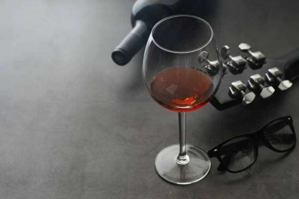 istock Guitar and high glass with red wine on a stone background. 1186935752