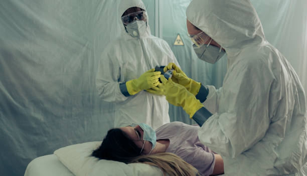 People attending to a woman with a virus lying on a stretcher Two people attending to a woman with a virus lying on a stretcher in a field hospital ebola stock pictures, royalty-free photos & images