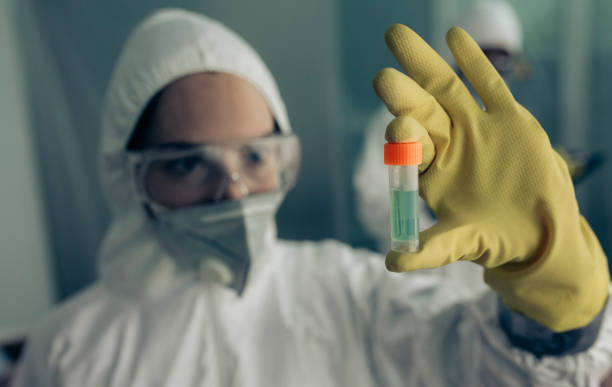 Woman with baceriological protective suit looking at an antidote vial stock photo