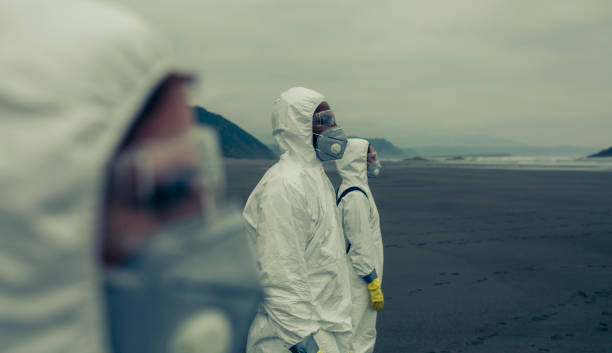 People with bacteriological protection suits looking at the sea People with bacteriological protection suits on the beach looking at the sea radioactive contamination photos stock pictures, royalty-free photos & images