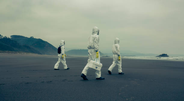 People with bacteriological protection suits walking on the beach Unrecognizable people with bacteriological protection suits walking on the sand of the beach walking beach women sadness stock pictures, royalty-free photos & images