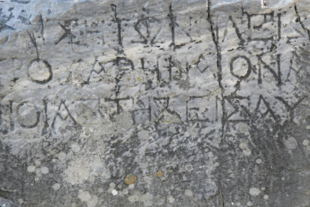 istock Half-erased ancient Greek letters embossed on an old gray marble slab 1186936473