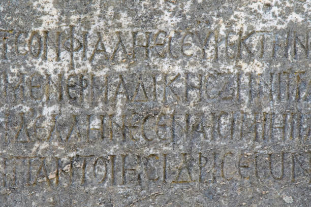 istock Half-erased ancient Greek letters embossed on an old gray marble slab 1186937110