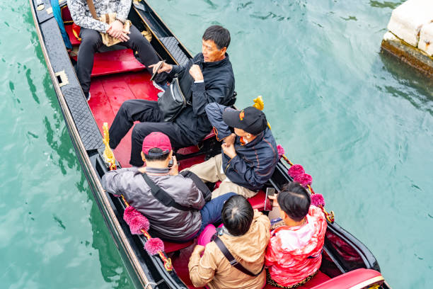A Gondola with tourists on board approaching the gondola stations at San Marco Square in Venice, Italy.