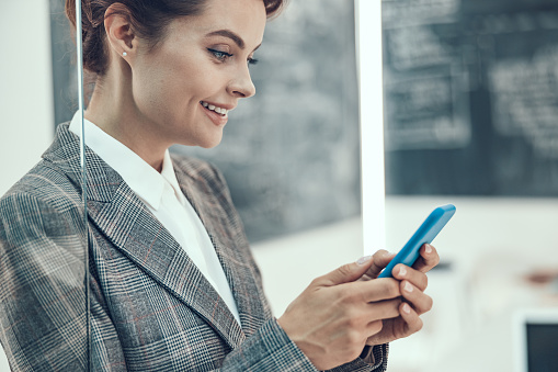 Happy beautiful lady using her modern gadget and smiling