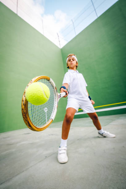 tenis chico golpea la pelota con su raqueta - tennis child childhood sport fotografías e imágenes de stock