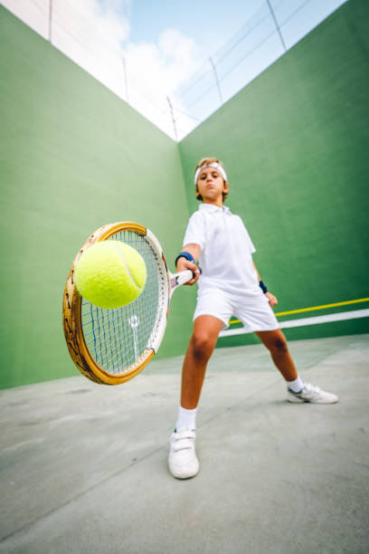 Tennis boy hits the ball with his racket stock photo