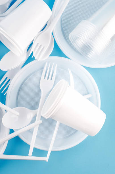 istock White Disposable cups, plates, forks, knives on light blue background close-up - Environmental problem concept 1186940088
