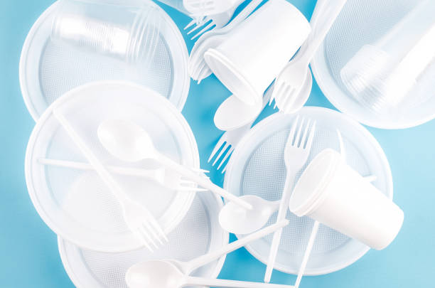 istock White Disposable cups, plates, forks, knives on light blue background close-up - Environmental problem concept 1186940850