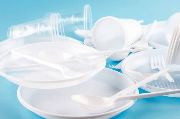 istock White Disposable cups, plates, forks, knives on light blue background close-up - Environmental problem concept 1186941205