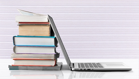 Stack of books and laptop, modern education background