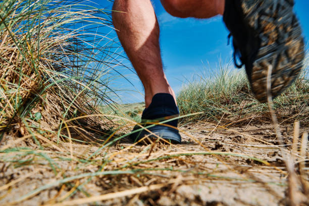 istock Motion blurred Mans feet and legs running along a path in sand dunes, Cornwall on a bright Autumn day. 1186945278