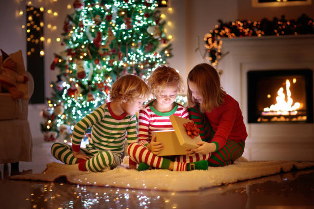 dziecko na choince. dzieci przy kominku na boże narodzenie - christmas child baby surprise zdjęcia i obrazy z banku zdjęć