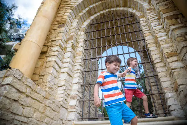 Photo of Young brothers near an ancient stone gate. Kids smiling and happy having leisure time on summer holiday