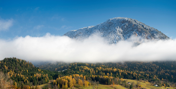 The first snow of the year covering the mountain top while below the clouds the vibrant fall colors shine on. Nikon D850. Converted from RAW.