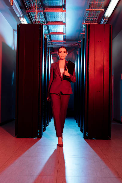 istock attractive businesswoman holding clipboard while walking in server room 1186956258