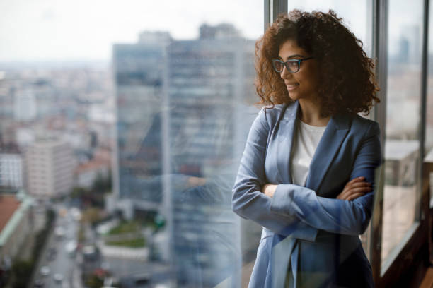 sorridente imprenditrice premurosa che guarda attraverso la finestra - looking through window window business women foto e immagini stock