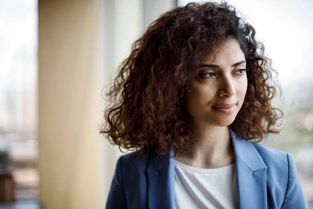 istock Smiling young businesswoman looking through window 1186957689