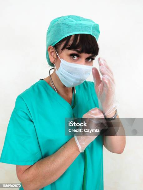 Woman Doctor Or Nurse With Mask Putting On Gloves Stock Photo - Download Image Now - Adult, Adults Only, Brown Hair