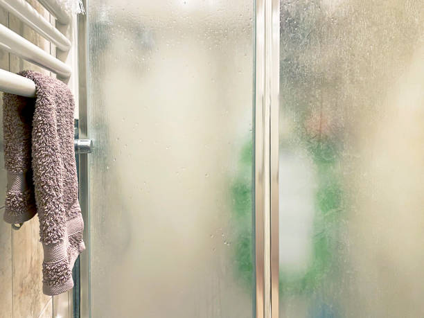 보라색 색 수건은 샤워 인클로저 근처의 흰색 라디에이터에 배치되어 있으며 욕실 내부에는 반투명 유리 문과 알루미늄 구조가 있습니다. - glass showcase interior bathroom shower 뉴스 사진 이미지