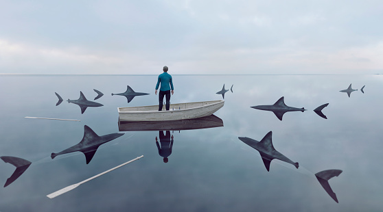 Perdido en el mar en bote de remos rodeado de tiburones en busca de una presa photo