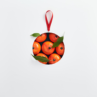 Christmas minimal concept - creative abstract christmas bauble made of tangerine with red ribbon. Christmas holiday layout. Minimal idea concept. Abstract mockup with bauble concept background minimal
