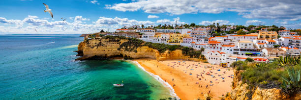 vista del villaggio di pescatori di carvoeiro con una bellissima spiaggia, algarve, portogallo. vista sulla spiaggia nella città di carvoeiro con case colorate sulla costa del portogallo. il villaggio di carvoeiro in algarve portogallo. - carvoeiro foto e immagini stock