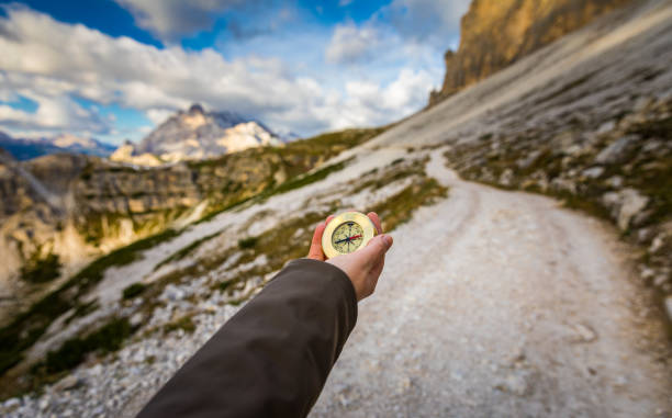 Explorer searching direction with compass in summer mountains, point of view.