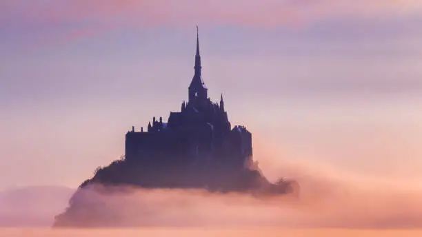 Panoramic view of famous Le Mont Saint-Michel tidal island in beautiful sunrise foggy light, Normandy, northern France