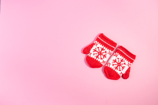 Christmas Red Knitted Mittens with Snowflake Motives on pink pastel trendy background. Christmas New Year minimal concept with copy space. Minimal winter background. Flat lay.