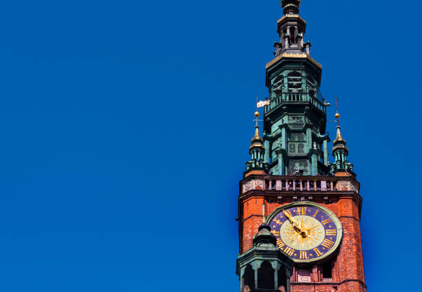 Clock tower of old historic brick town hall in Gdansk old town, Poland against blue sky with copy space
