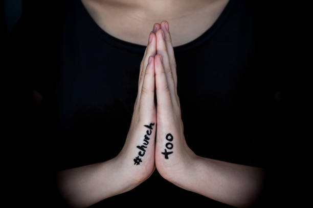 Close-up of woman's hands held in prayer with hashtag #churchtoo written on hands The #churchtoo movement is a sister movement to #metoo, protesting and bringing to light the cover-up of sexual abuse in both Catholic and Protestant churches clergy stock pictures, royalty-free photos & images