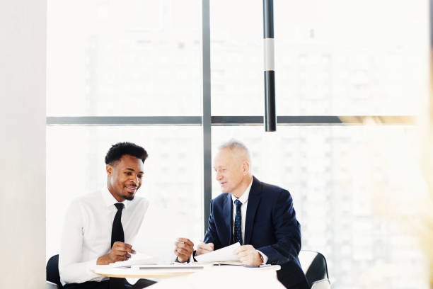istock Positive enterprising multi-ethnic colleagues sitting at table in contemporary office and discussing budget implementation while doing paperwork 1186986692