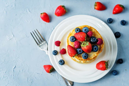 pancakes with strawberries, blueberries and raspberries. toning. selective focus