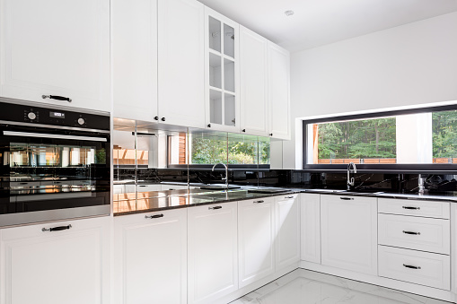 Luxury kitchen interior, with black countertops and white cupboards
