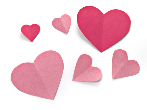Six pink and red paper hearts on a white background.