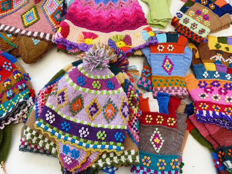 Lima, Peru - November 2, 2019: Handicraft souvenirs from Peru: colorful woolen knitted hats and gloves with tradition design at the Indian market in Lima, Peru