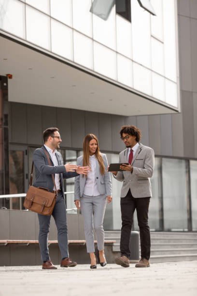 istock Three people standing in front of a corporate building. 1187000487