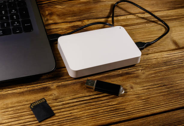 istock External HDD connected to laptop computer, SD memory card and USB flash drive on a wooden desk. Concept of data storage 1187000798